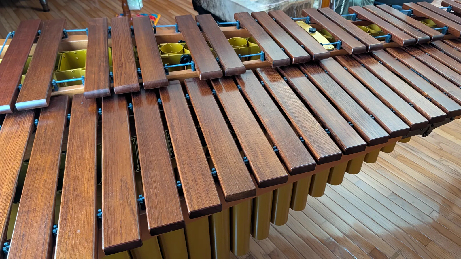 Close view of wooden marimba bars arranged in two rows above the resonator openings